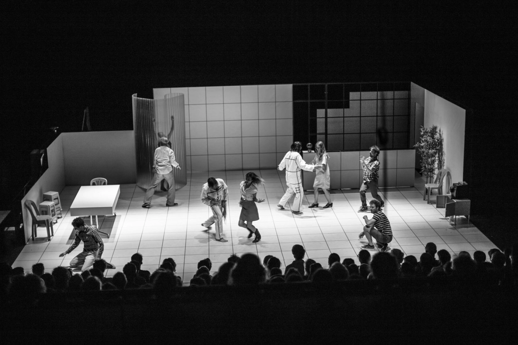 Black and white stage photo of actors in a modern play, dramatic mood.