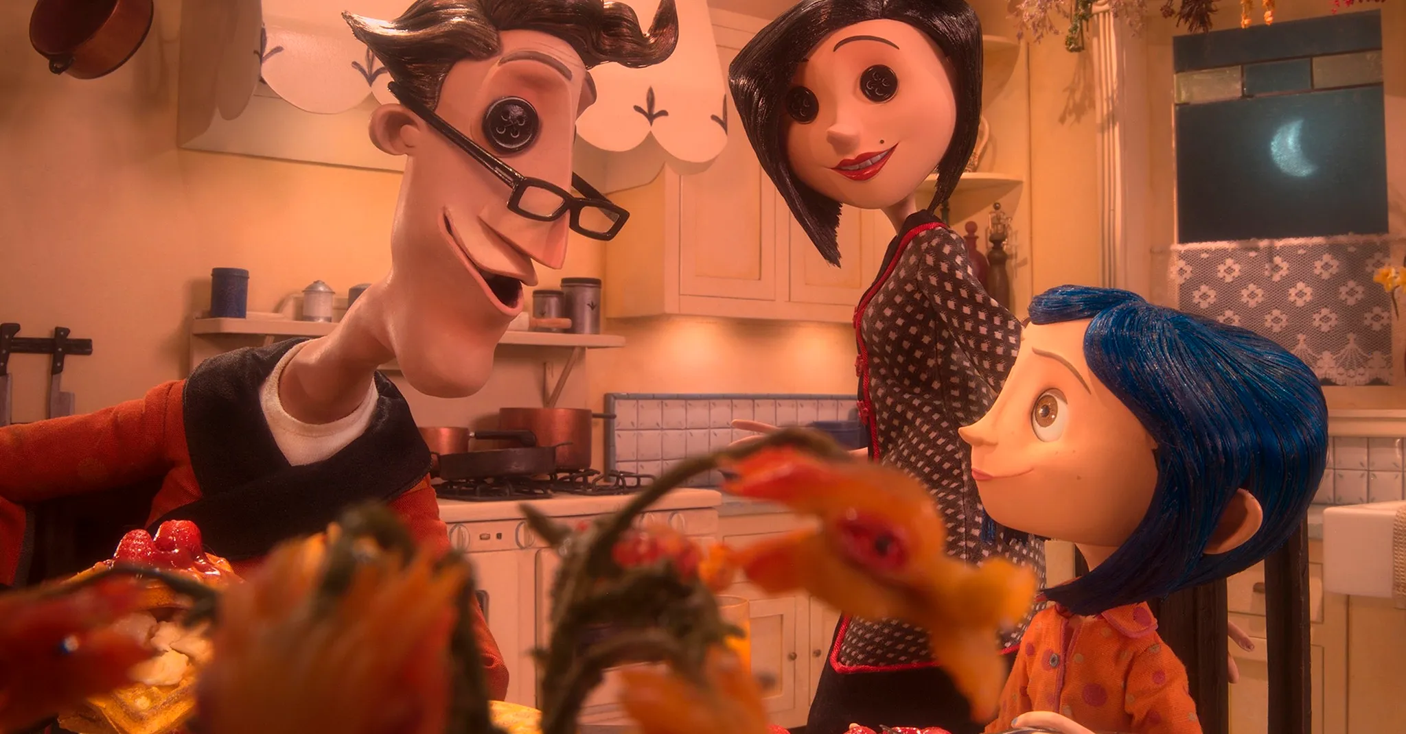 Stop-motion animation still: Coraline's family in a warm, stylized kitchen.