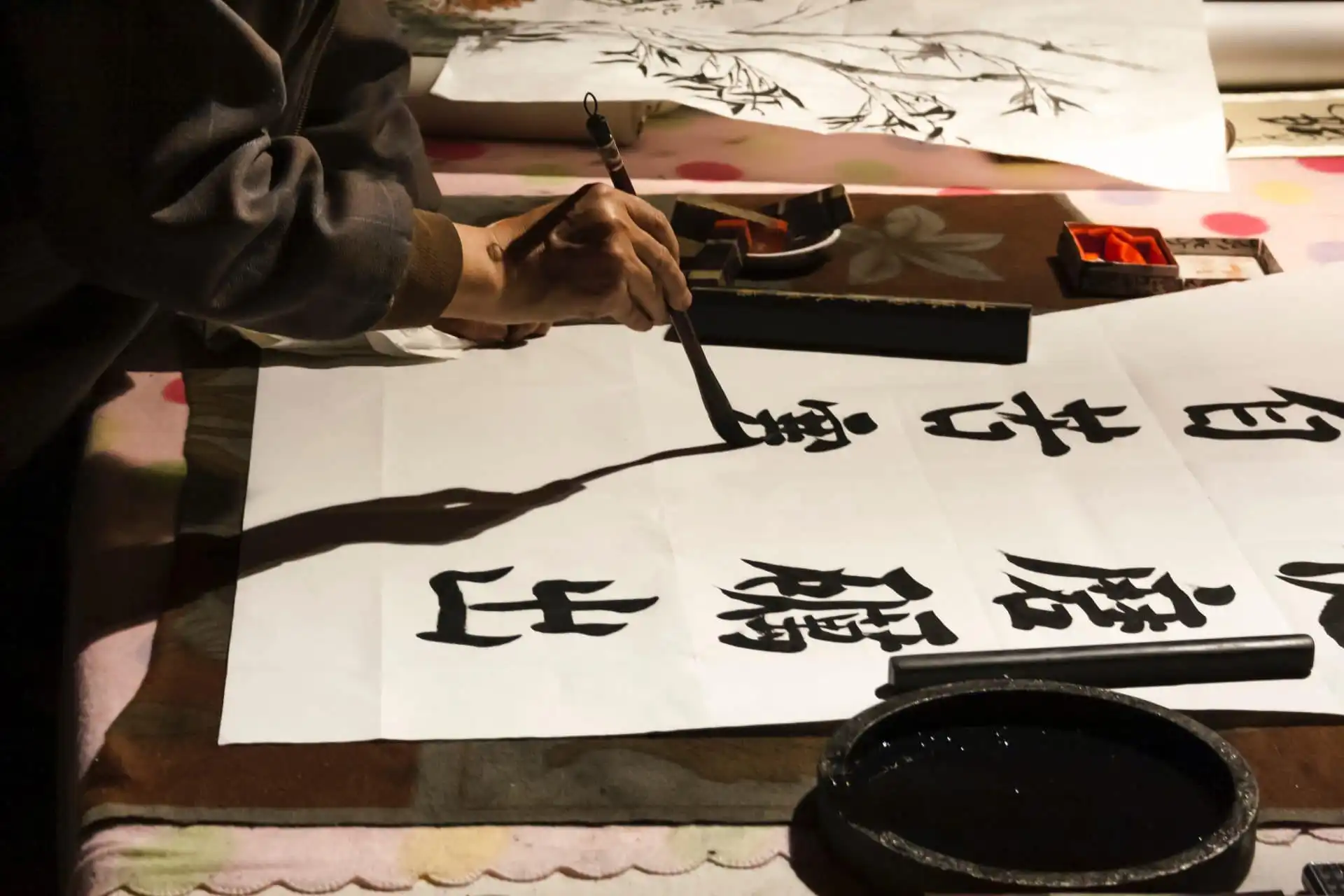 Chinese calligraphy on paper, artist painting characters with brush, traditional art.