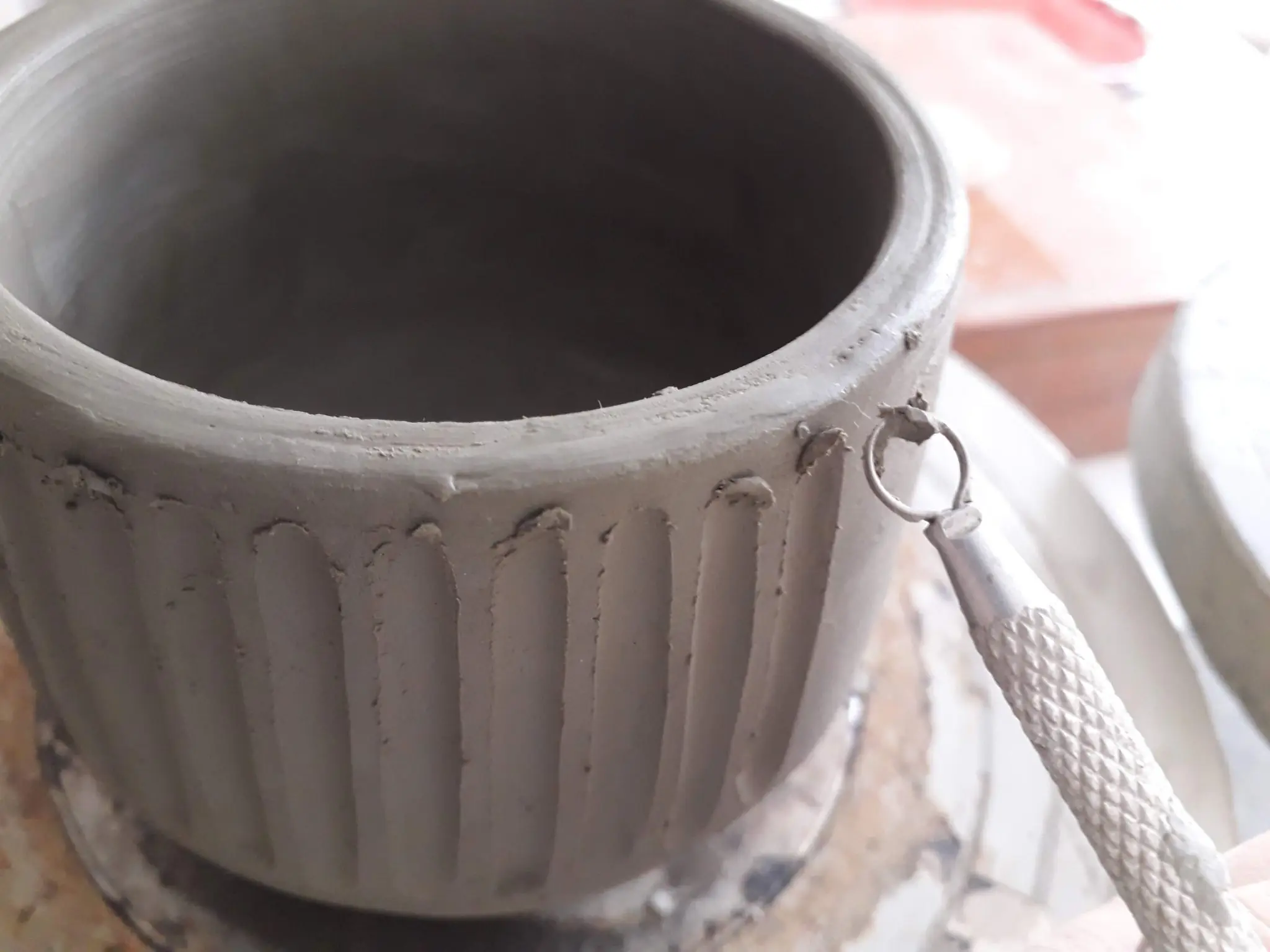 Close-up of clay pot being textured with a loop tool, artisanal pottery.