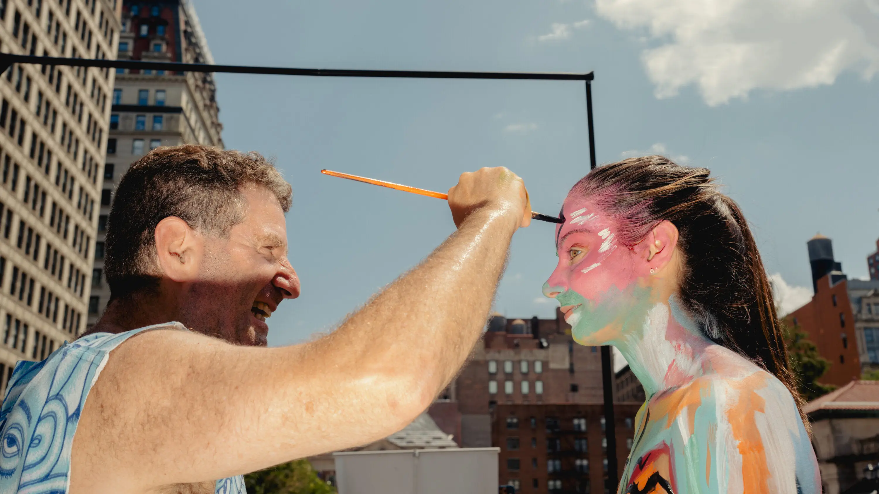 Body painting portrait of a woman with vibrant colors, urban backdrop, outdoor setting.
