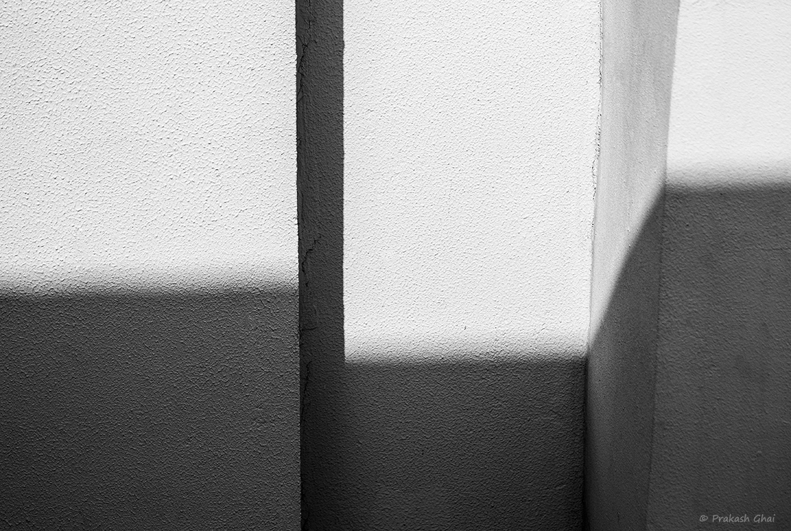 Abstract black and white architectural photograph with strong shadows and textures.