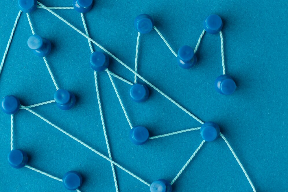 Abstract network of blue pins and string on teal background.