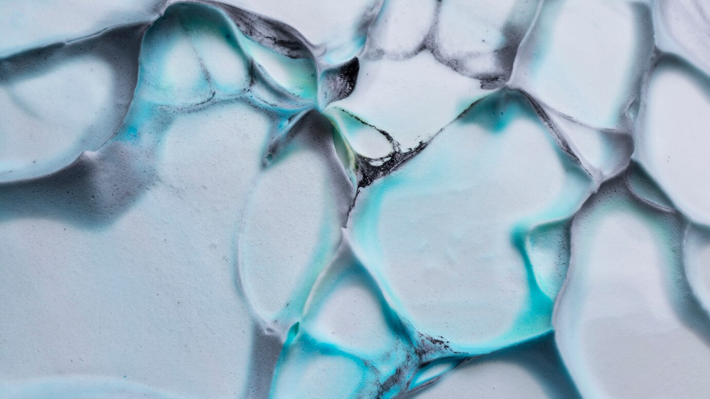 Abstract macro photograph of swirling blue and white foam with dark accents.
