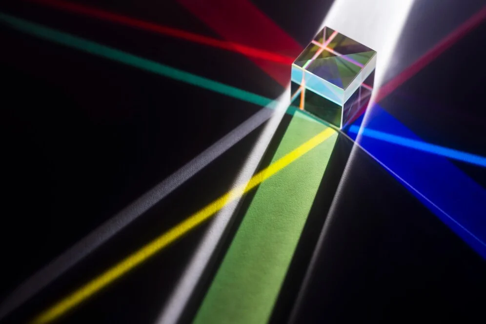 Prism refracting white light into a spectrum of colors on black background.